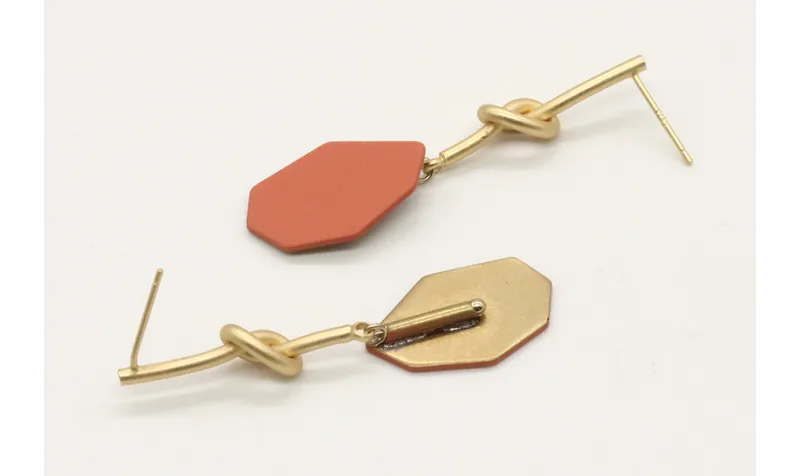 Pendientes perno nudo largo en oro mate y pieza es