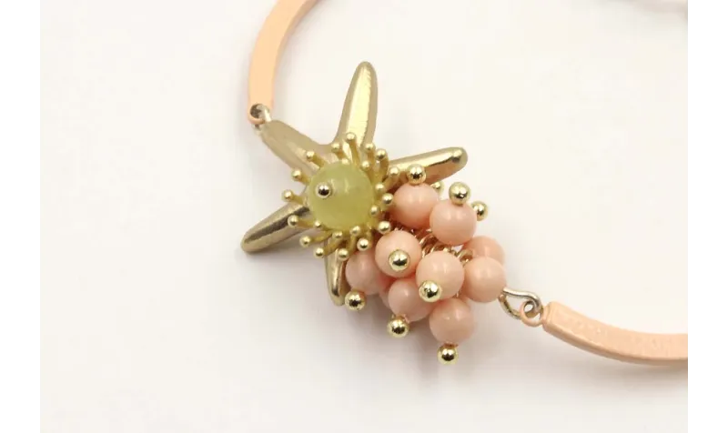Pulsera semirigida con bolas rositas, estrella oro