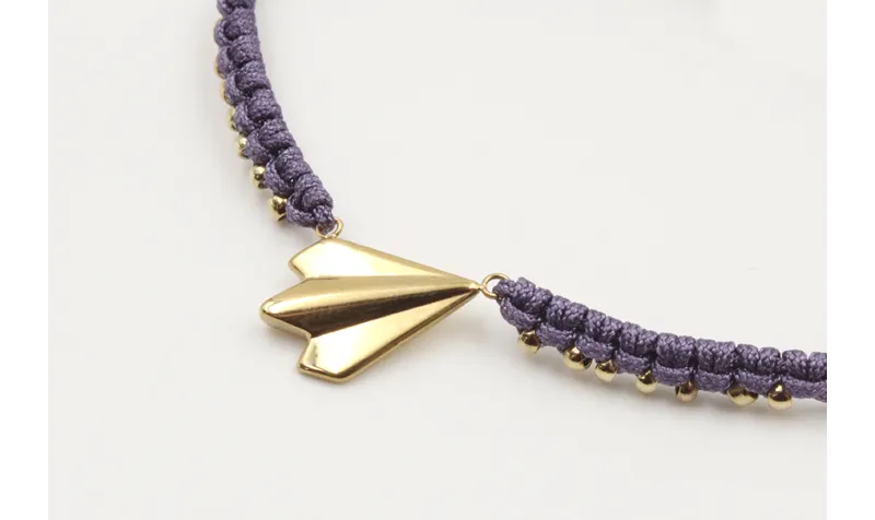 Pulsera macrame morado con bolitas doradas y avión