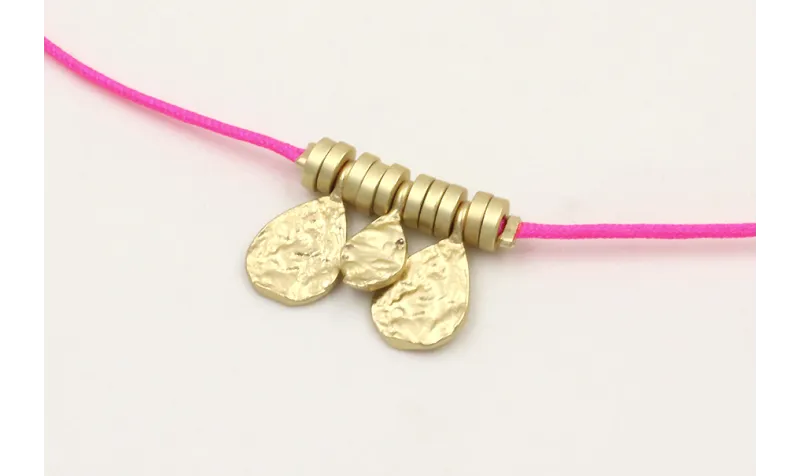Pulsera hilo fucsia con colgantes laminas labradas